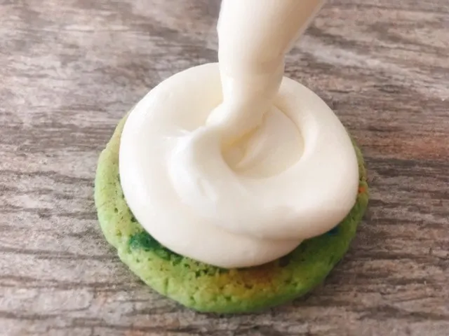 White cream filling being piped onto one side of a Shamrock Shake Whoopie Pie