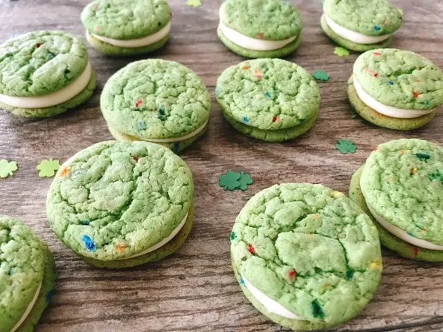 Shamrock Shake Whoopie Pies on a wooden background with tiny green shamrocks.
