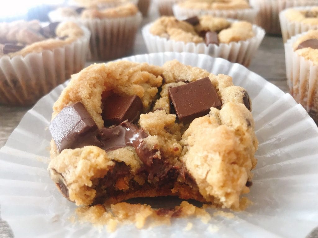 A close up of a deep dish chocolate chip cookie with chocolate chunks and a bite taken out.