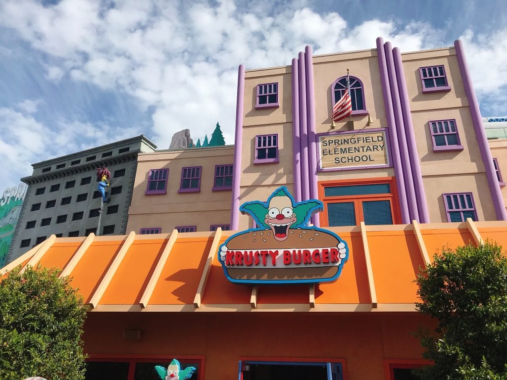 A building with a clown holding a hamburger that says, “Krusty Burger”