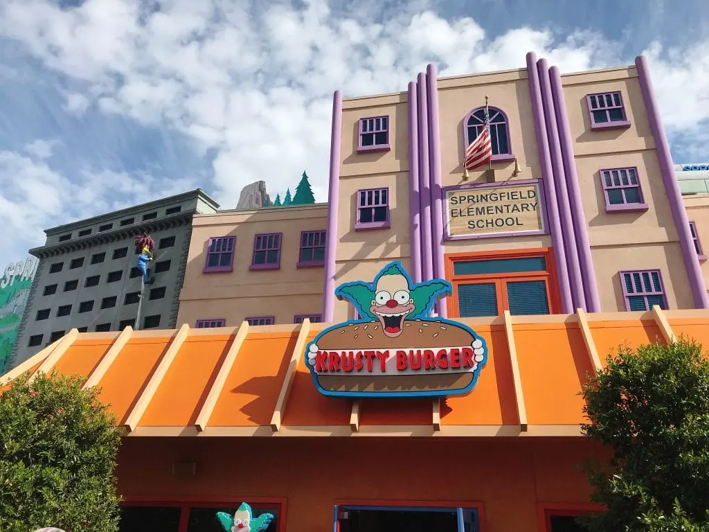 A building with a clown holding a hamburger that says, “Krusty Burger”
