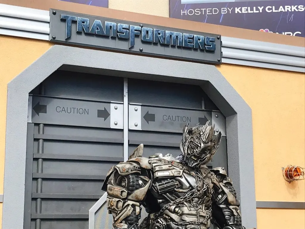 A large Transformer in front of metal doors with a sign that says “Transformers”