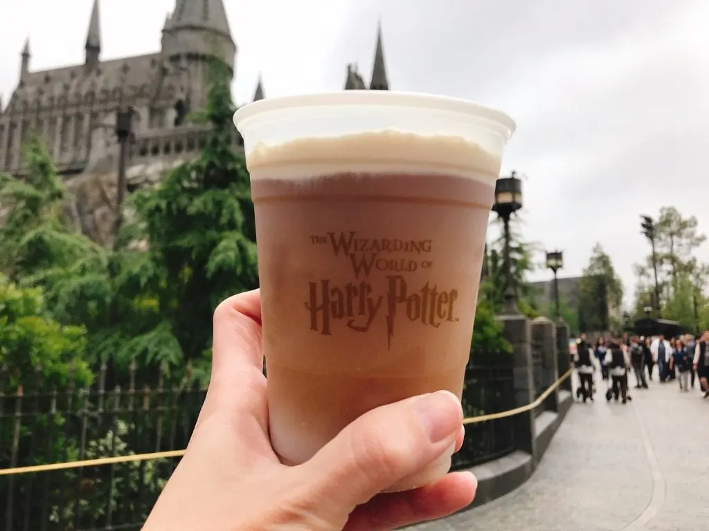 A cup of Frozen Butterbeer in front of Hogwarts Castle at the Wizarding World of Harry Potter at Universal Studios Hollywood.