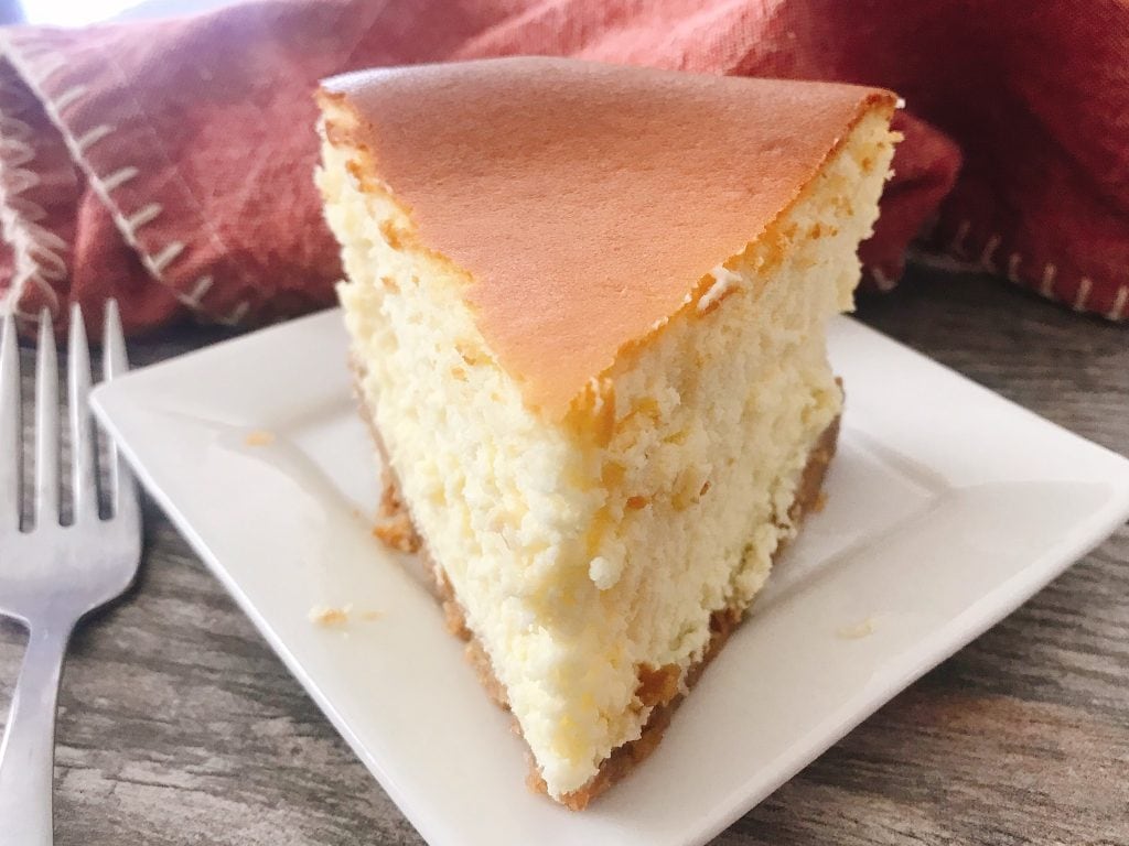 A slice o New York Cheesecake on a white plate.