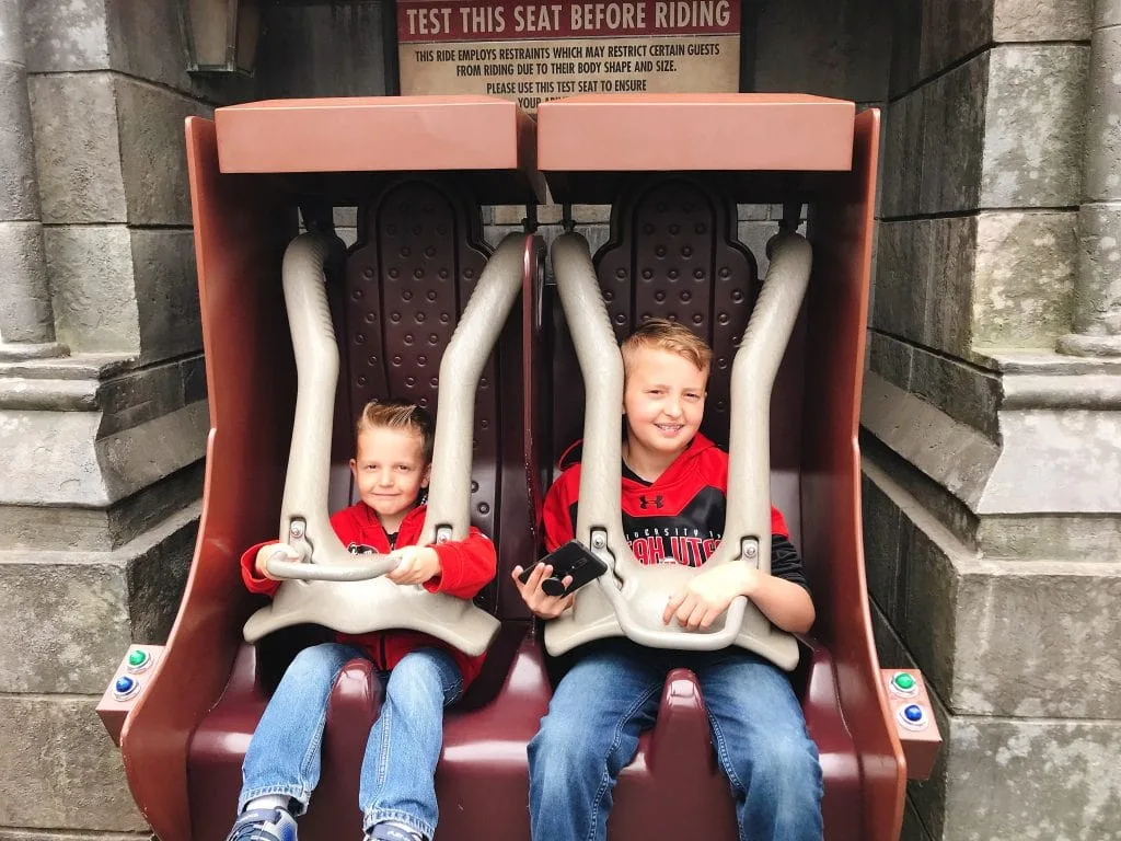 Two kids sitting in roller coaster seats at the entrance of “Harry Potter and the Forbidden Journey” in the Wizarding World of Harry Potter inside Universal Studios Hollywood.