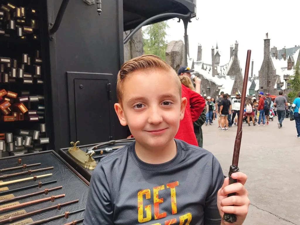 A boy holding a magic wand at The Wizarding World of Harry Potter inside Universal Studios Hollywood.