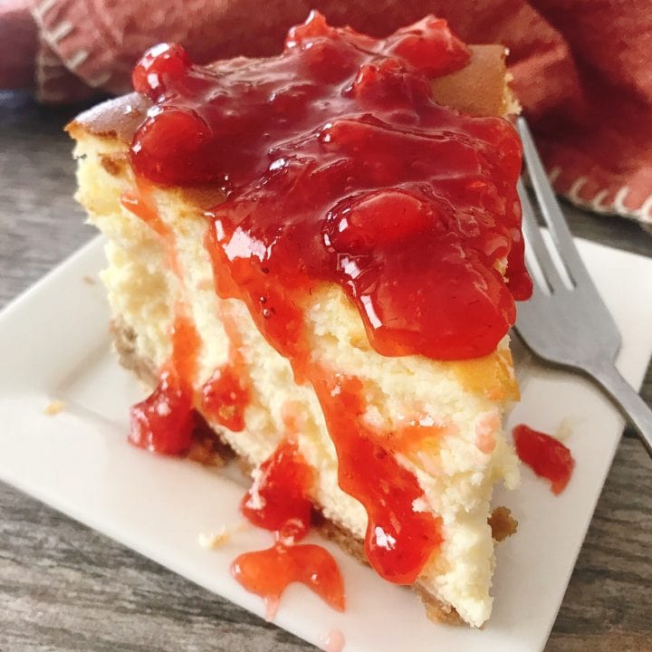 A slice of classic New York cheesecake topped with strawberry sauce.