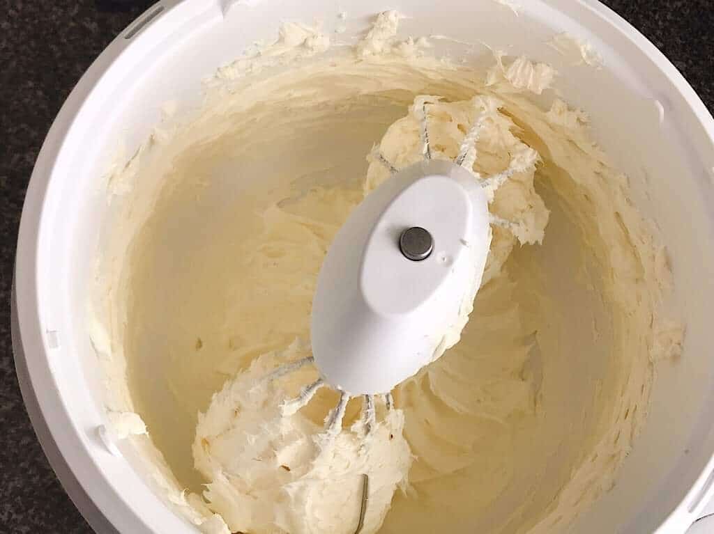 Cream cheese in the bowl of a stand mixer.