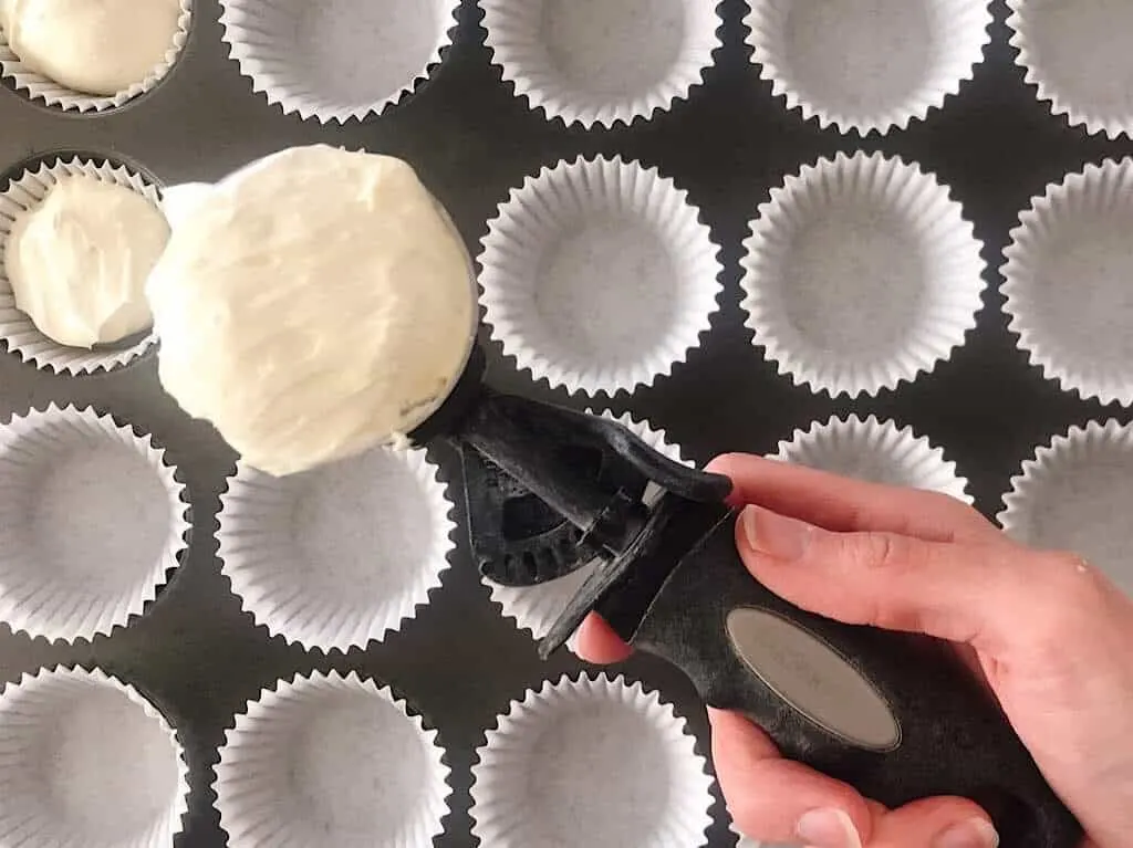 a scoop of cheesecake batter over a muffin pan.