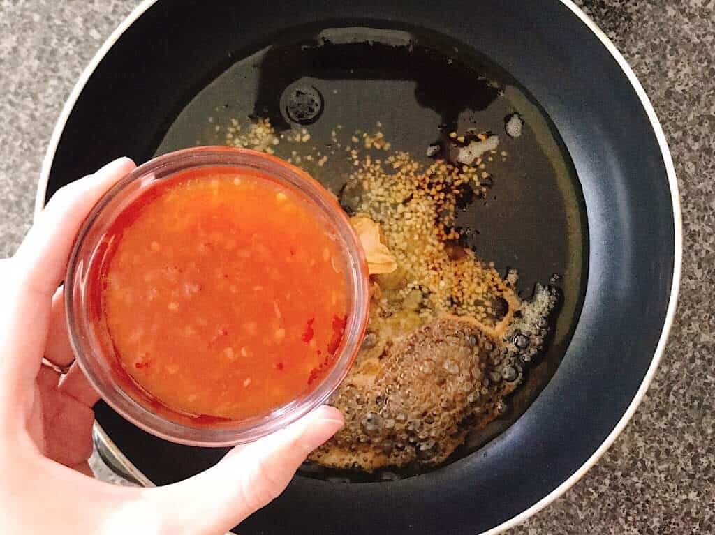 A bowl of sweet chili sauce over a pan of Spicy Peanut Sauce.