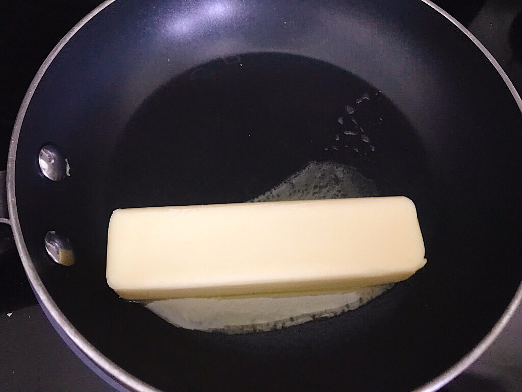 A stick of butter melting in a pan.