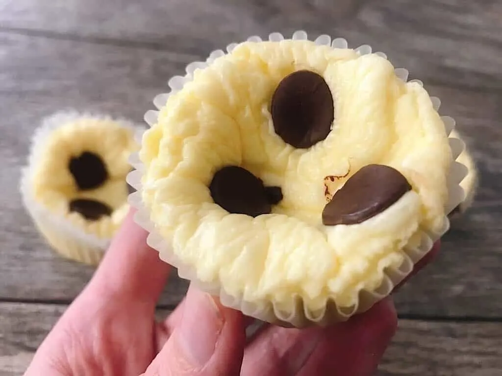 A hand holding a low carb cheesecake muffin with chocolate chips.