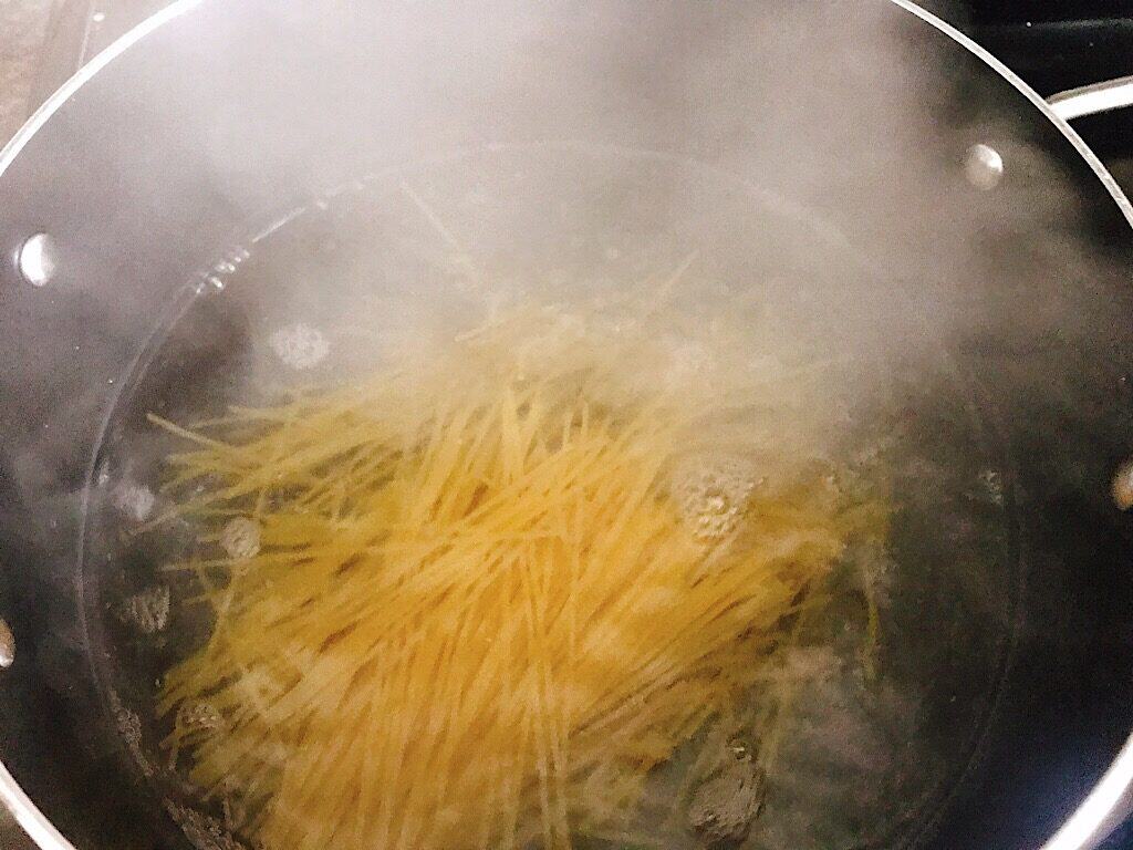Spaghetti noodles in a pan of boiling water.