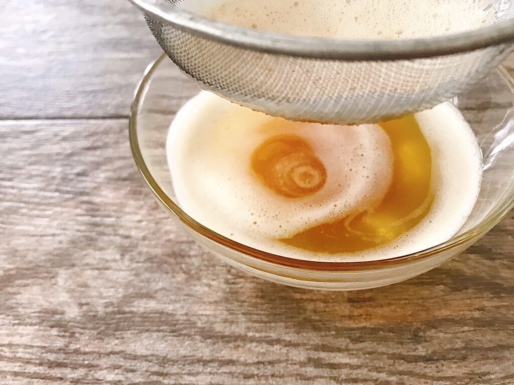 A strainer over a bowl of browned butter.