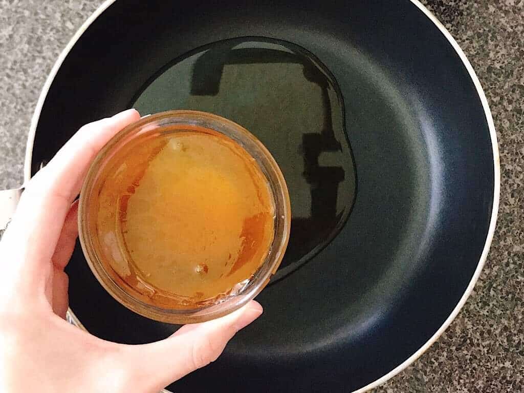 A bowl of honey being held over a saucepan.