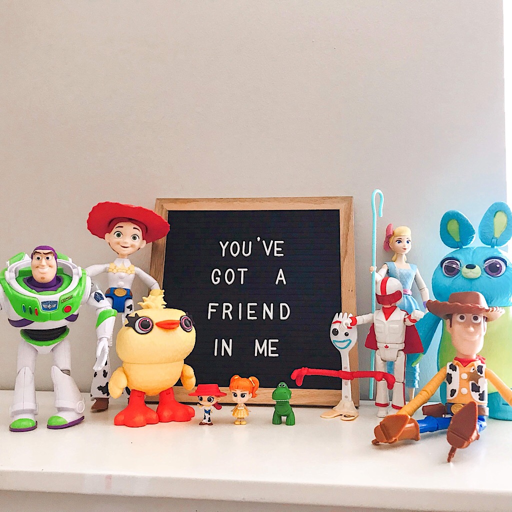 The toys from Toy Story 4 lined up with a sign that says “You’ve Got a Friend in Me”