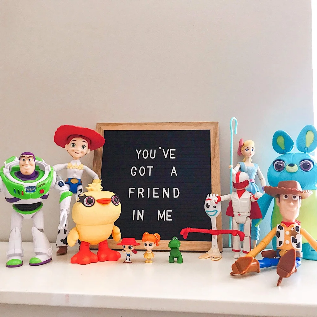 The toys from Toy Story 4 lined up with a sign that says “You’ve Got a Friend in Me”