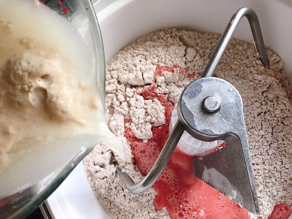 Yeast and water being poured into a stand mixer to make Red Velvet Cake Mix Cinnamon Rolls with Cream Cheese Frosting