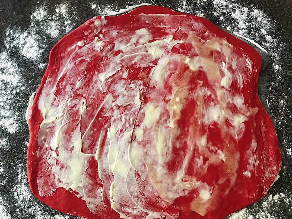 Butter spread over red velvet cinnamon roll dough