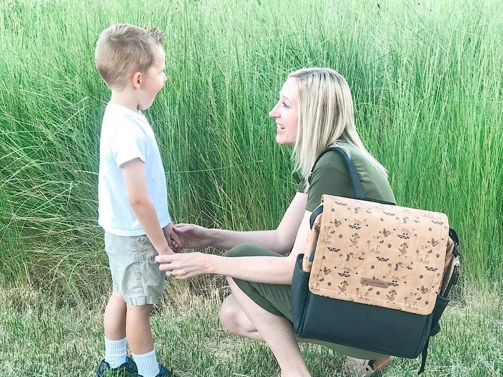 A boy and his mom in front of green grass.