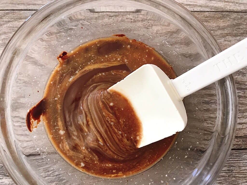A spoon stirring melted chocolate and peanut butter.