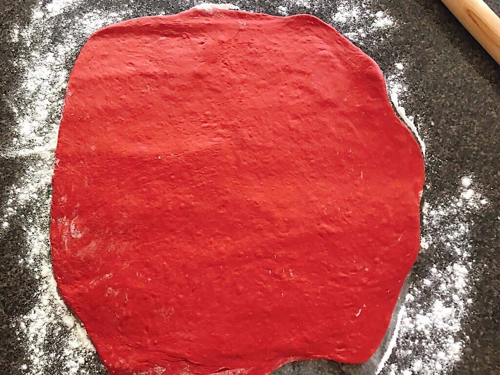 Red Velvet dough on a floured counter top with a rolling pin