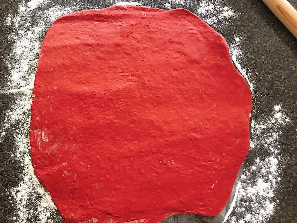 Red Velvet dough on a floured counter top with a rolling pin