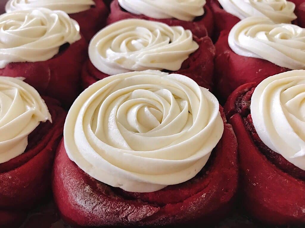 Cream cheese frosting on red velvet cinnamon rolls