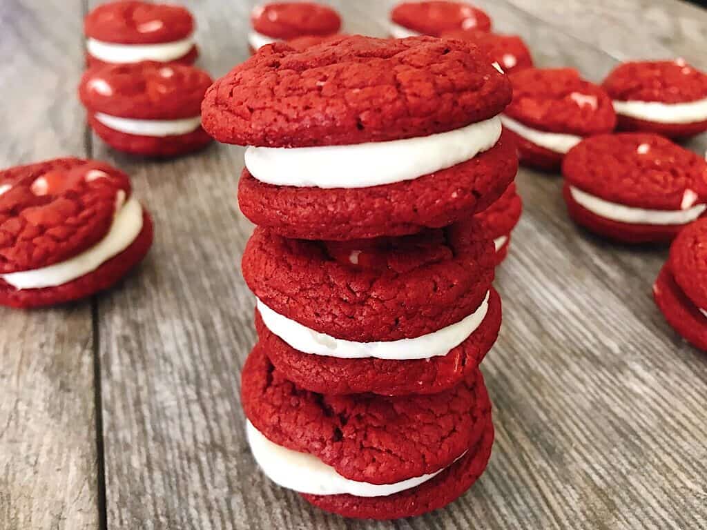 A stack of red velvet cake mix sandwich cookies with cream cheese frosting