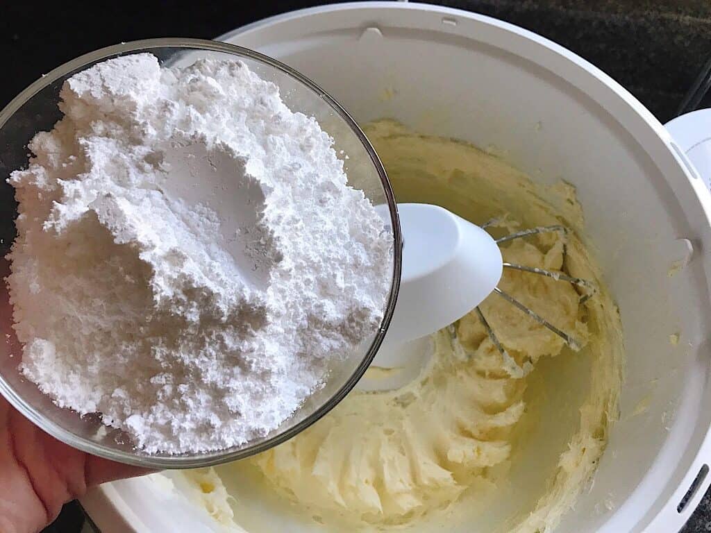 A bowl of powdered sugar over a stand mixer to make cream cheese frosting for Red Velvet cake mix cinnamon rolls