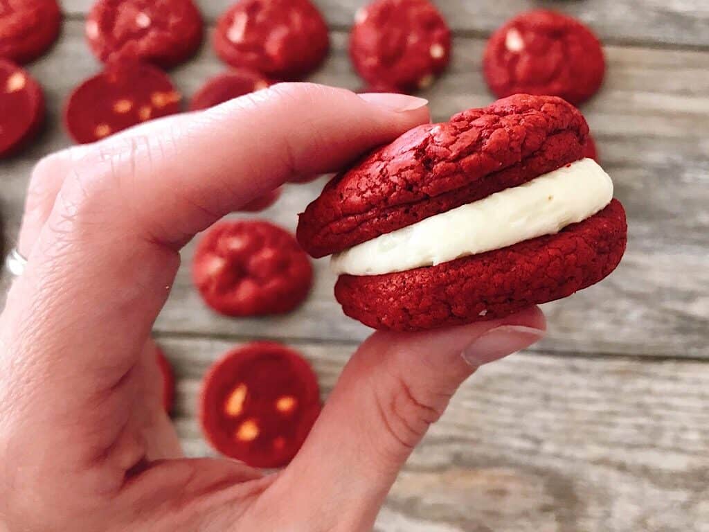 A red velvet sandwich cookie with cream cheese frosting filling