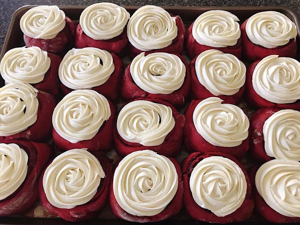 A pan of red velvet cake mix cinnamon rolls with cream cheese frosting.
