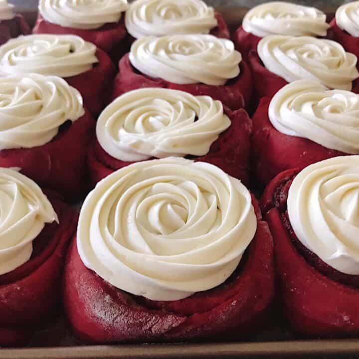 A pan of red velvet cinnamon rolls with cream cheese frosting.