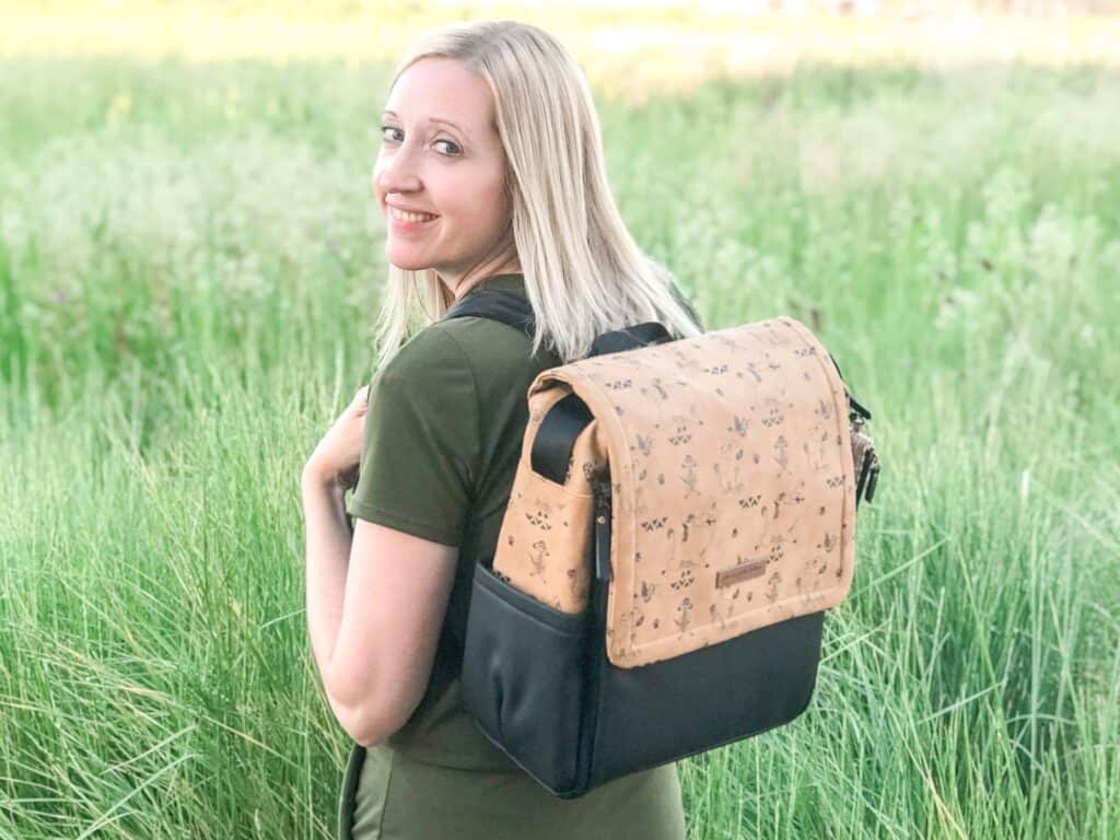 A woman wearing a backpack in a field.