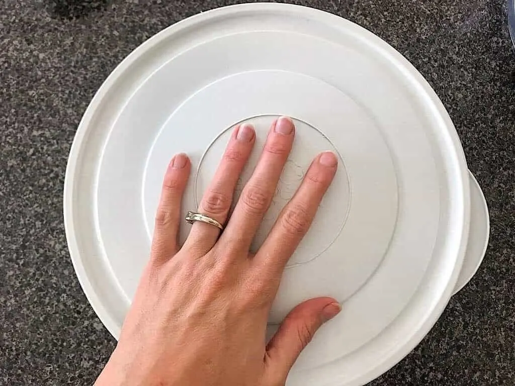 A hand over a covered bowl
