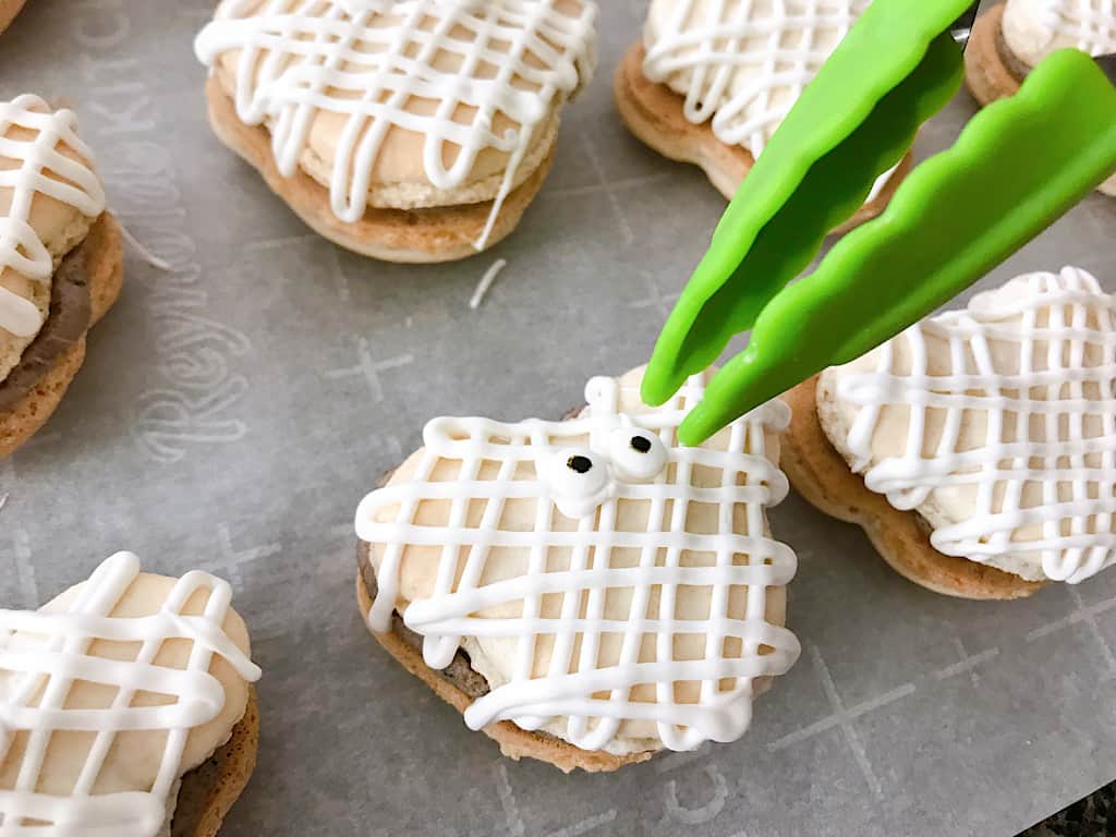 Tongs putting eyes on Mickey Mummy Macarons