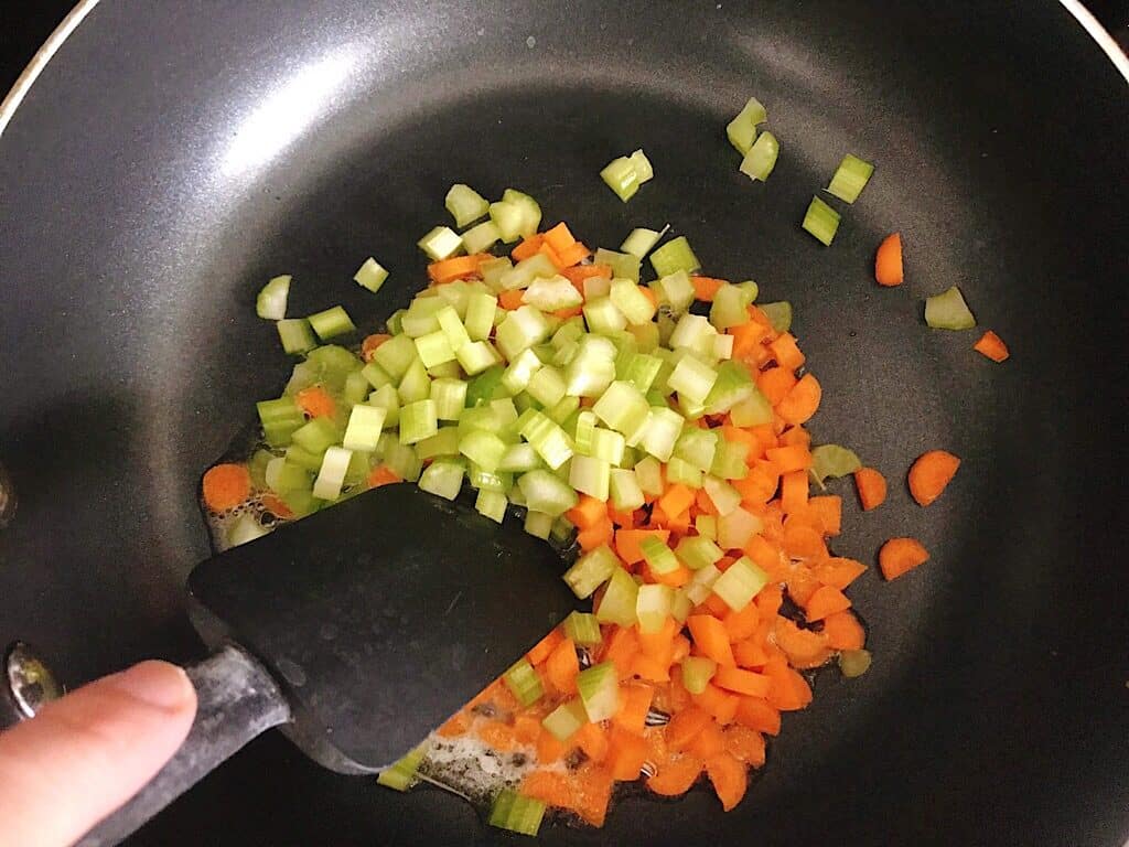 Chopped carrots and celery sautéing in a pan