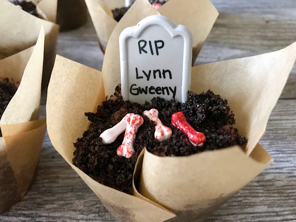 A graveyard cupcake with a candy headstone and bones.