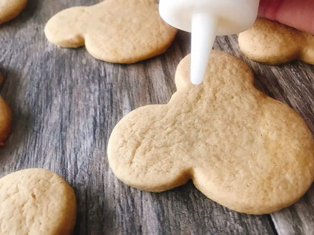 Mickey Mouse shaped Gingerbread Sugar Cookies being frosted