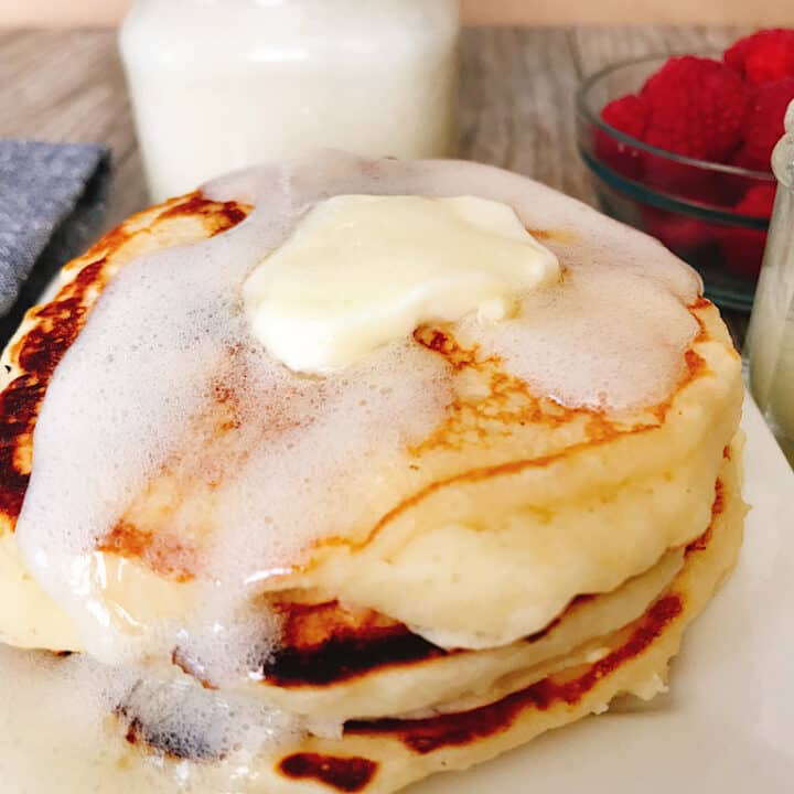 A plate of fluffy buttermilk pancakes covered with buttermilk syrup