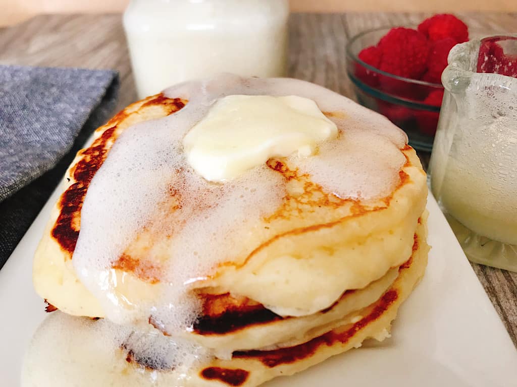 A plate of fluffy buttermilk pancakes covered with buttermilk syrup