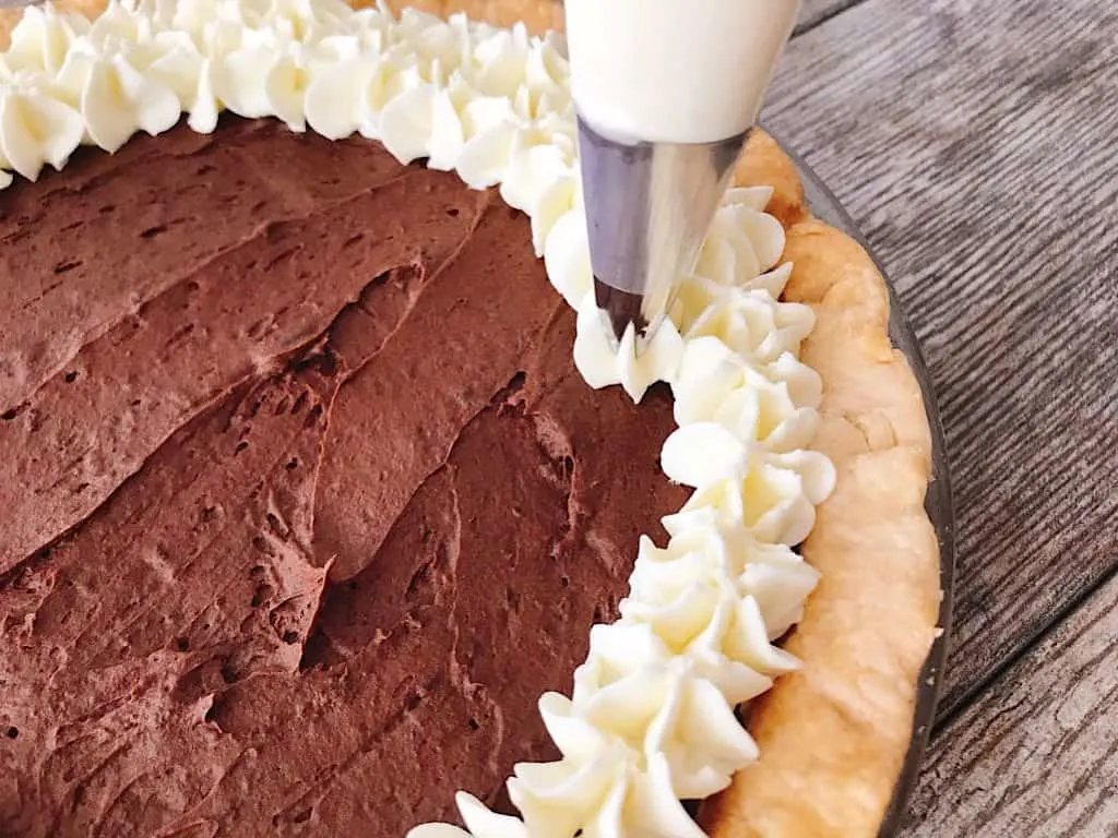 Whipped cream piped on chocolate ganache pie