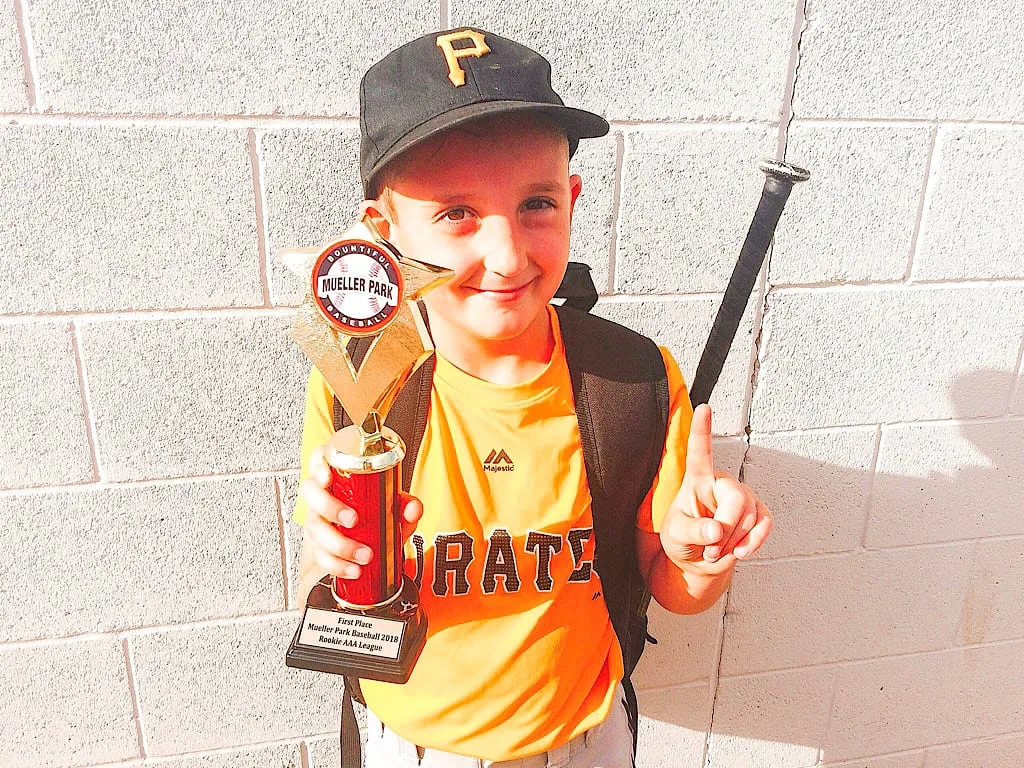 A young baseball player with a trophy
