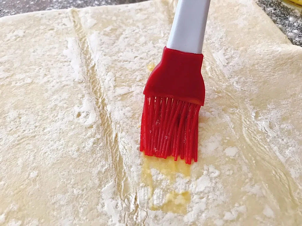 A pastry brush and puff pastry dough