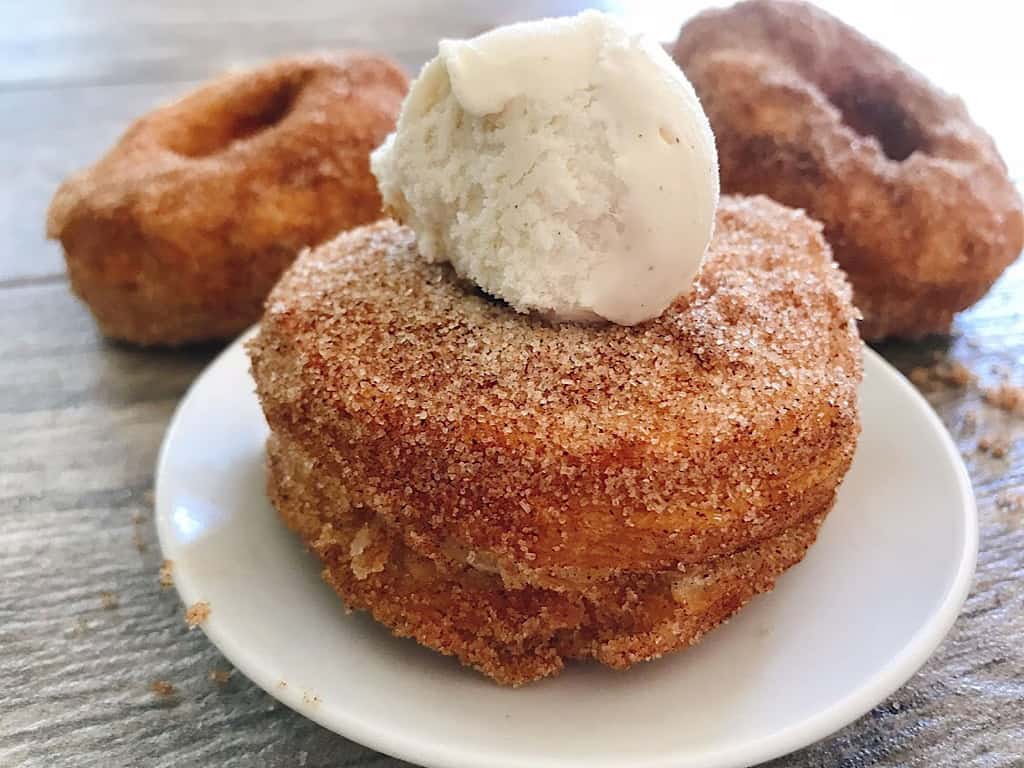 A cronut on a plate topped with ice cream