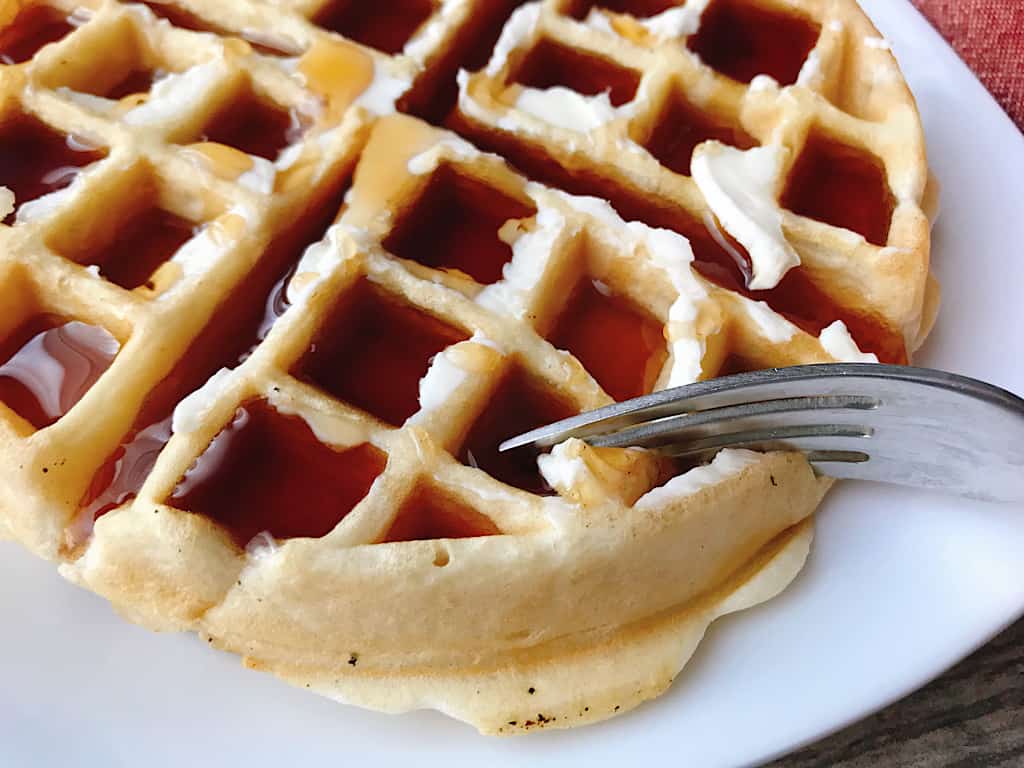 A fork cutting a waffle.