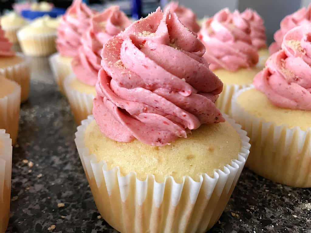 A vanilla cupcake with strawberry frosting