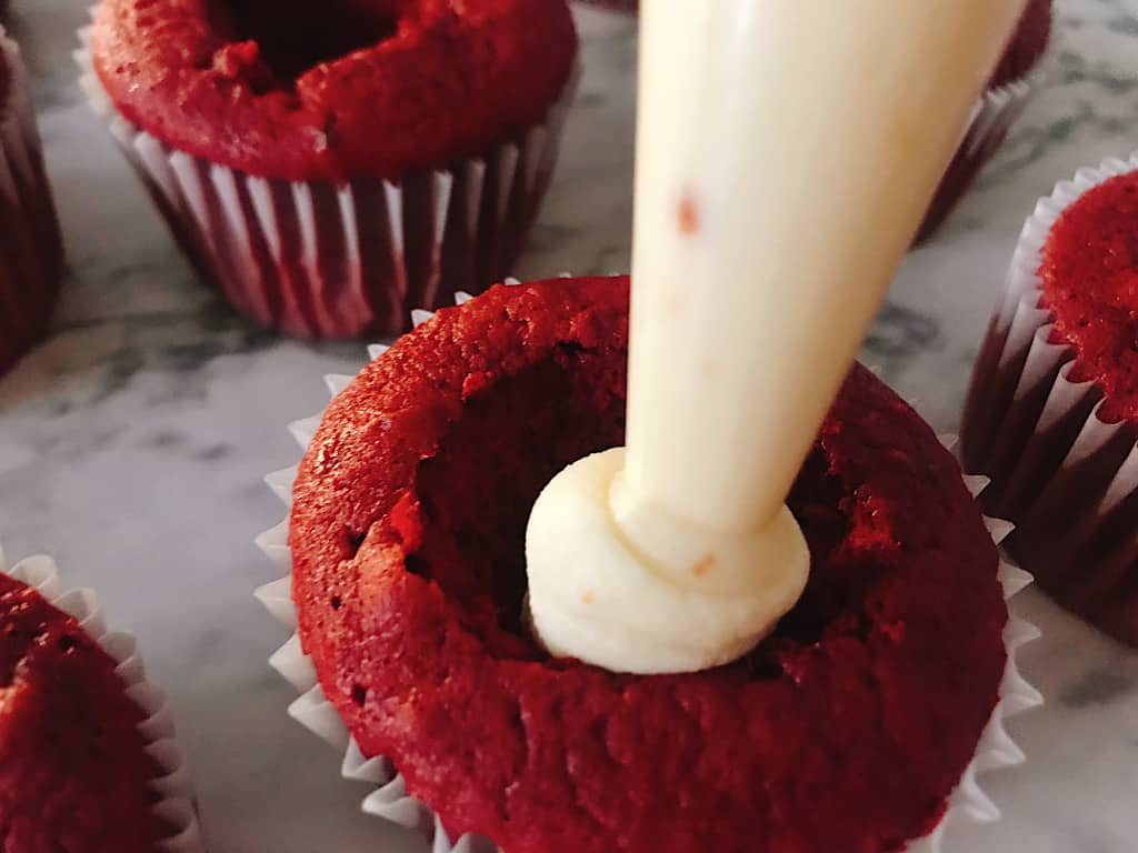 Cheesecake piped into red velvet cupcakes