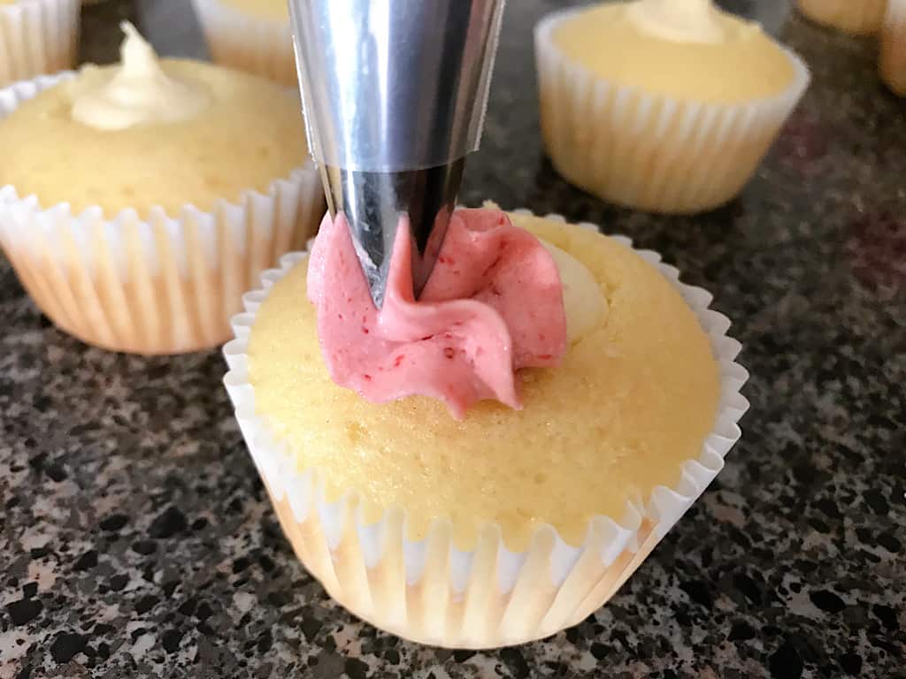 Strawberry buttercream frosting piped onto a strawberry cheesecake cupcake