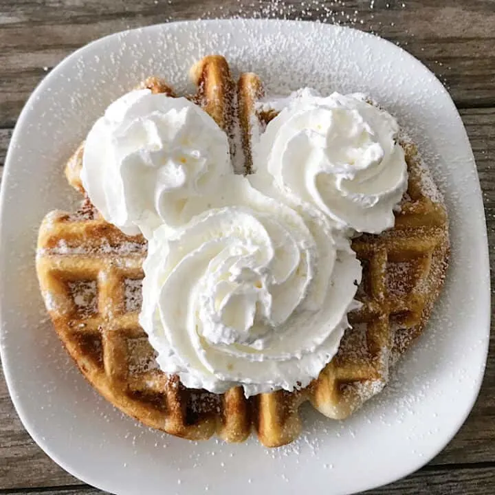 A funnel cake waffle with Mickey Mouse-shaped whipped cream